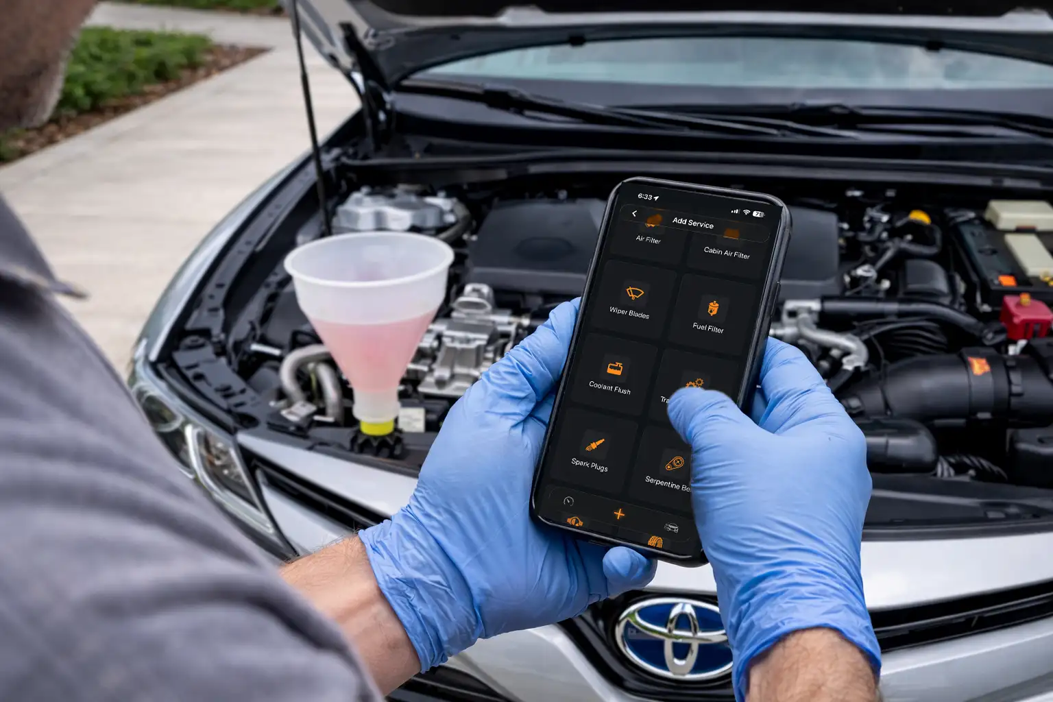 Logging Toyota Camry maintenance on a mobile phone during coolant service